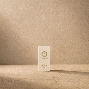 A small white rectangular ZANNIS Aeon product box stands centered on a textured beige surface against a matching beige wall, with soft directional light and a long shadow.