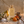 A rectangular glass perfume bottle labeled ZANNIS AFON stands centered on a stone surface, surrounded by pear halves, white flowers, coarse salt, amber honey, a honey dipper, and a textured stone backdrop.