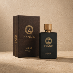 Zannis Axios Extract de Parfum bottle in matte black with a textured gold cap, standing next to its dark brown packaging box on a textured beige surface.