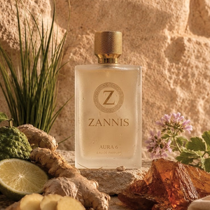 A bottle of Zannis Aura 6 Eau de Parfum is centered, surrounded by natural ingredients and botanicals including ginger, lime, herbs, and amber resin against a textured stone background.