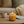Candle with a lit flame on a wooden table in a cozy living room setting.